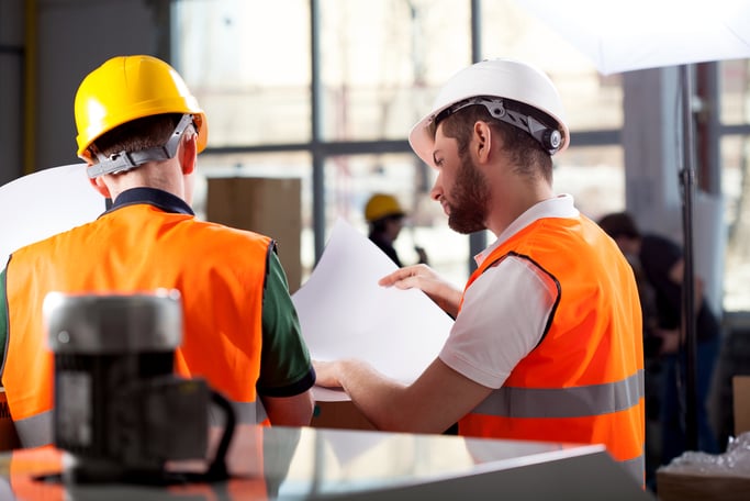 Male factory worker and supervisor are analyzing plans